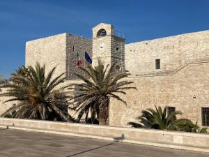 a large brick building with a clock tower and palm trees at Loft Carrettieri Affittacamere by Le Marinelle in Trani