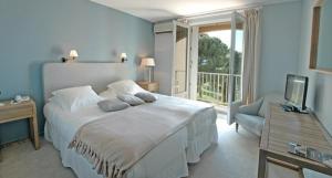 a bedroom with a large white bed and a balcony at Hotel Santa Maria in Saint-Florent