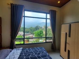 - une chambre avec une grande fenêtre offrant une vue dans l'établissement Bobo Queen House 5 villa baba ( mountain view), à Puncak