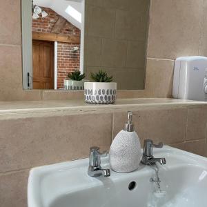 a bathroom sink with a soap dispenser on it at The Old Dairy in Hickling