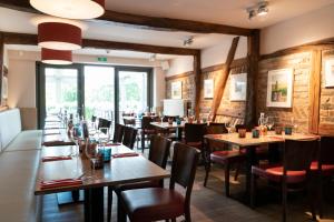 een restaurant met houten muren en tafels en stoelen bij Hotel Le Fournil in Redu