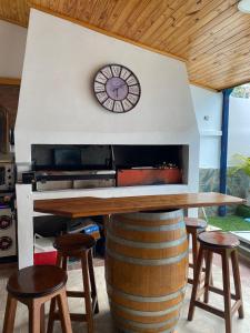a large wooden table with stools and a clock on a wall at Refugio El Jazmín in Posadas