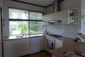 a kitchen with white cabinets and a sink and a window at Sea Banksia in Denmark