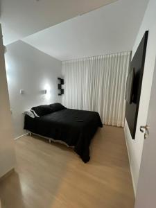 een slaapkamer met een zwart bed in een witte kamer bij Blend Marista - apt 1 Qt in Goiânia