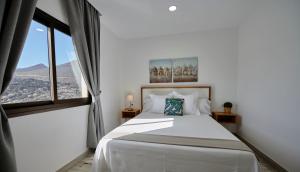 a bedroom with a large white bed with a window at ABLANCAS - La Restinga in La Restinga