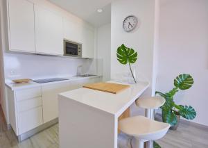 a white kitchen with a counter and a clock on the wall at ABLANCAS - La Restinga in La Restinga