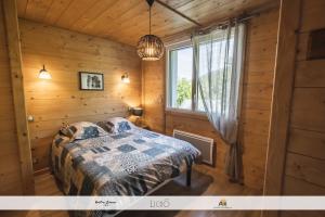 a bedroom in a log cabin with a bed and a window at Les Balcons Montagnards in Ax-les-Thermes