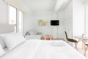 a white bedroom with a white bed and a chair at Adorable sunny studio with private balcony I in Athens