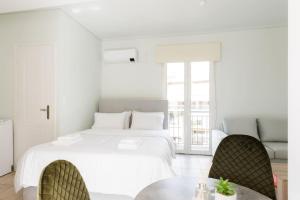 a white bedroom with a bed and a table at Adorable sunny studio with private balcony I in Athens