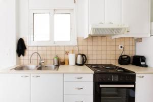cocina blanca con fregadero y fogones en Adorable sunny studio with private balcony I, en Atenas