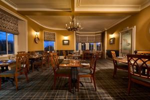 a restaurant with wooden tables and chairs and a chandelier at Ulbster Arms Hotel near Thurso in Halkirk