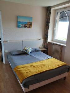 ein Schlafzimmer mit einem Bett mit einer gelben Decke in der Unterkunft L'Albatros in Perros-Guirec