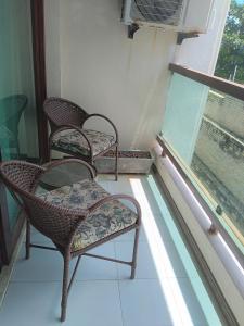 two chairs and a table in front of a window at Flat a beira mar, vista lateral - Araça 408 in Natal