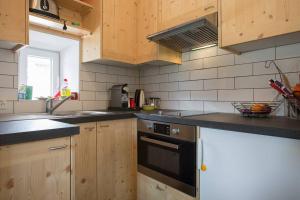 una cocina con armarios de madera y horno negro en Mini maison à Sierre linges et nettoyage compris, en Sierre