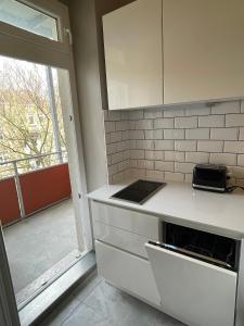 a kitchen with a white counter and a window at Altbaucharme Deluxe mit Balkon in zentraler Lage in Kiel