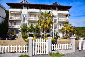 a white picket fence in front of a building at White Sea View Apartment Velipoje in Velipojë