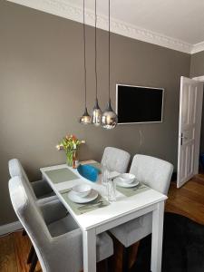a white dining room table with chairs and a tv at Altbaucharme Deluxe mit Balkon in zentraler Lage in Kiel
