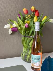 a bottle of wine next to a vase of flowers at Altbaucharme Deluxe mit Balkon in zentraler Lage in Kiel