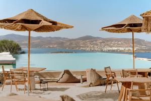a beach with tables and chairs and umbrellas at Mythic Paros , Adults Only in Agia Irini Paros