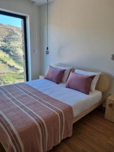 a bedroom with a large bed with a large window at Casa das Marucas in Peso da Régua