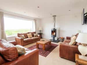 a living room with leather furniture and a fireplace at Lurach House in Port Appin