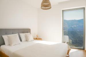 a bedroom with a white bed with a large window at Casa das Marucas in Peso da Régua