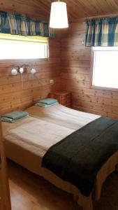 ein Schlafzimmer mit einem Bett in einer Holzhütte in der Unterkunft Petäjäkylä in Kuusamo