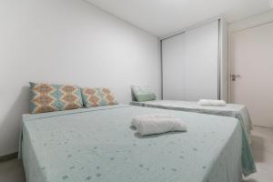 a bedroom with two beds with white walls at Excelente Casa de Temporada em Porto de Galinhas casa 3 in Porto De Galinhas