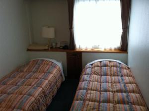 two beds in a room with a window at Hotel Kokusai Plaza (Kokusai-Dori) in Naha