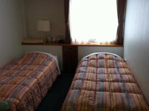 a bedroom with two beds in a room with a window at Hotel Kokusai Plaza (Kokusai-Dori) in Naha