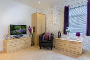 uma sala de estar com uma televisão, uma cadeira e um armário em The Richmond Bed and Breakfast - Adults only em Shanklin