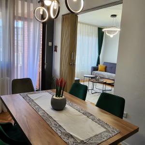 a dining room table with green chairs and a living room at Shpetim's Apartment in Pristina