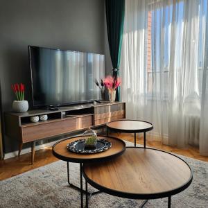a living room with two tables and a flat screen tv at Shpetim's Apartment in Pristina