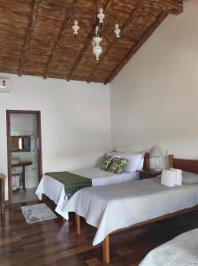 a bedroom with two beds and a wooden ceiling at Pedacinho do céu in Tiradentes