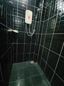 La salle de bains est pourvue de carrelage noir, d'une douche et d'un distributeur de savon. dans l'établissement Modern resort..โมเดิร์นรีสอร์ท, à Thang Kwian