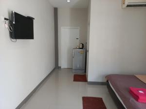 Zimmer mit einem Kühlschrank und einem TV an der Wand in der Unterkunft Modern resort..โมเดิร์นรีสอร์ท in Thang Kwian