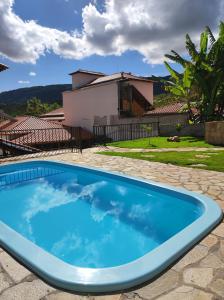 a blue swimming pool in front of a house at Pedacinho do céu in Tiradentes