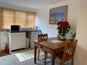 a kitchen with a wooden table and chairs and a table and a sink at Self contained annex with bedroom bathroom sitting room and kitchenette in Emsworth