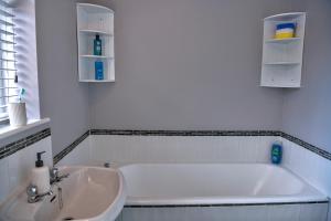 a white bathroom with a tub and a sink at Oakland in Kettering