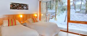 a bedroom with two beds and a window with snow at Kalasur Patagonia Apart Hotel in San Martín de los Andes