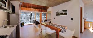 a kitchen with a table and some white chairs at Kalasur Patagonia Apart Hotel in San Martín de los Andes