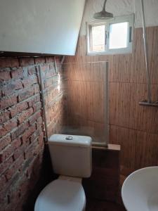 ein Bad mit einem WC und einer Ziegelwand in der Unterkunft La fortuna in Las Toscas