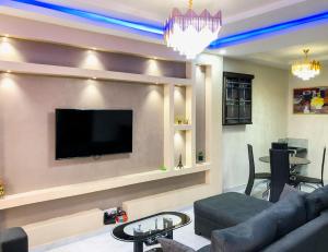 a living room with a couch and a tv on a wall at Crayford Homes in Ikeja