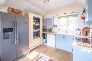 een keuken met blauwe kasten en een koelkast bij Church Farm House Campsea Ashe in Woodbridge