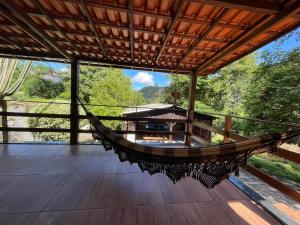 a hammock on the deck of a house with a view at Confortável Chalet na Serra proximo ao Centro in Nova Friburgo