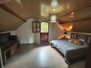 ein Schlafzimmer mit einem Bett und einem TV in einem Zimmer in der Unterkunft Confortável Chalet na Serra proximo ao Centro in Nova Friburgo