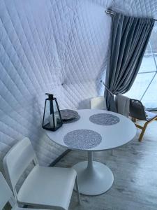 - une table et des chaises blanches dans une chambre avec fenêtre dans l'établissement Glempings Anemones, à Plieņciems
