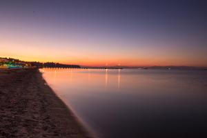 una puesta de sol sobre un cuerpo de agua con una playa en Hotel Pithari en Agia Triada