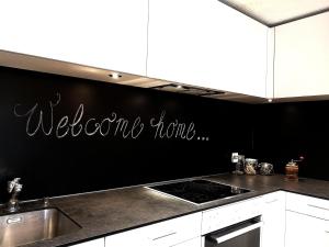 eine Küche mit einer schwarzen Wand und einem Willkommensschild in der Unterkunft Urchige 2-Zimmerwohnung in Matten