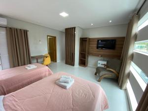 a hotel room with two beds and a tv at Hotel C&A in Bofete